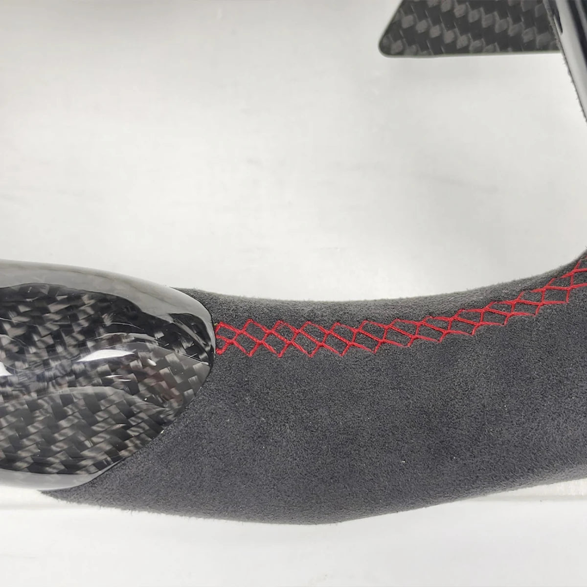 Detalle de la costura roja sobre Alcántara y la fibra de carbono